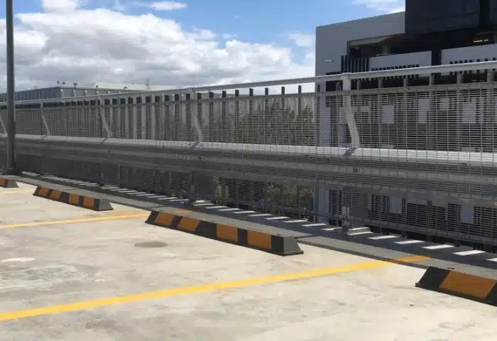 Rhino Stop Car park barrier next to wheel stops in parking spaces